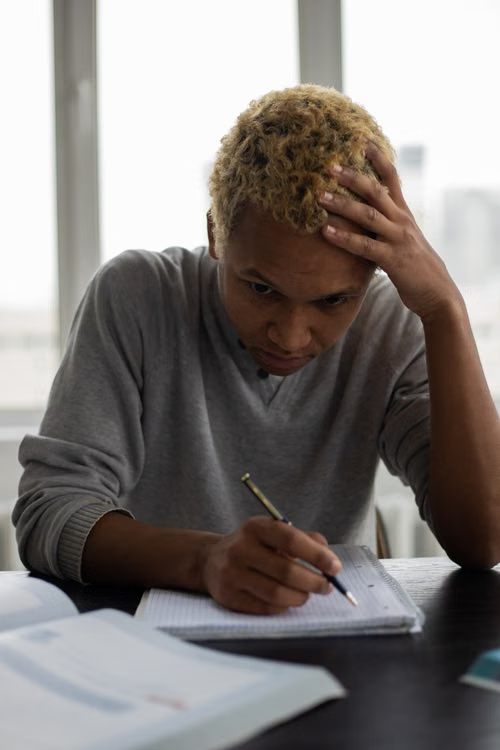 A student reflecting and writing in a notebook